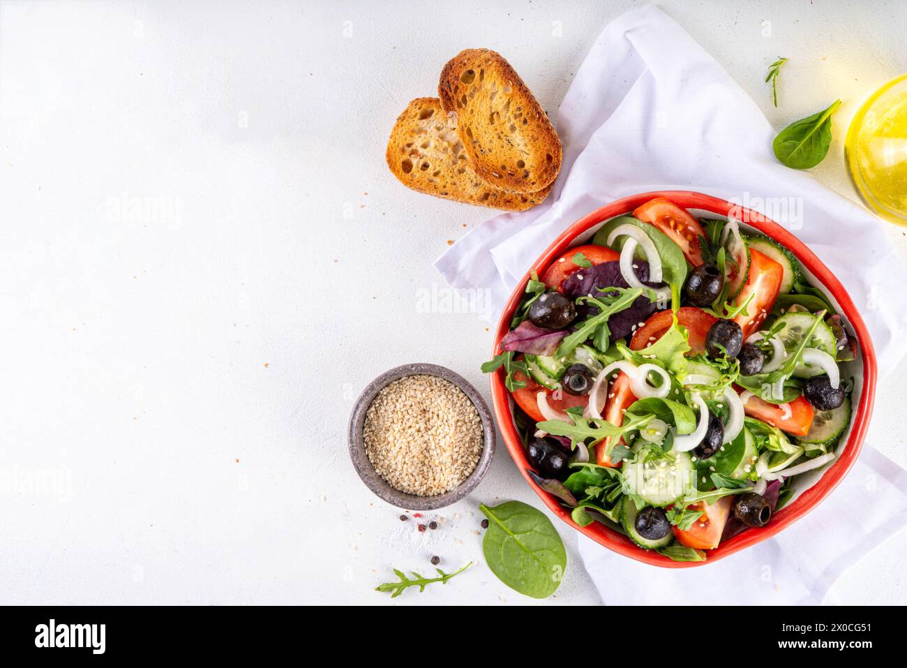 Salade biologique fraîche avec tomates, concombre, olives et légumes verts. Nourriture végétalienne saine, salade grecque de légumes méditerranéens sur table de cuisine blanche co Banque D'Images