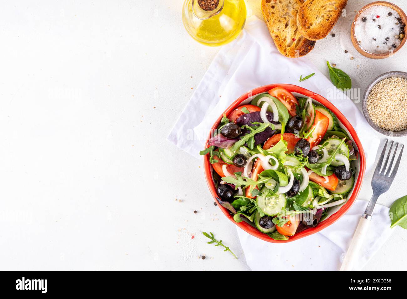 Salade biologique fraîche avec tomates, concombre, olives et légumes verts. Nourriture végétalienne saine, salade grecque de légumes méditerranéens sur table de cuisine blanche co Banque D'Images