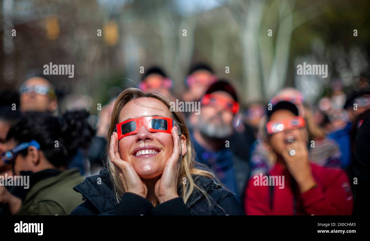 Des centaines de personnes se rassemblent à Flatiron Plaza à New York pour une fête d'observation à regarder, portant leurs lunettes de protection, l'éclipse solaire le lundi 8 avril 2024. New York City n'était pas sur le chemin de la totalité avec la lune couvrant 89% du soleil pendant la fenêtre de 15h15 à 15H30. (© Richard B. Levine) Banque D'Images