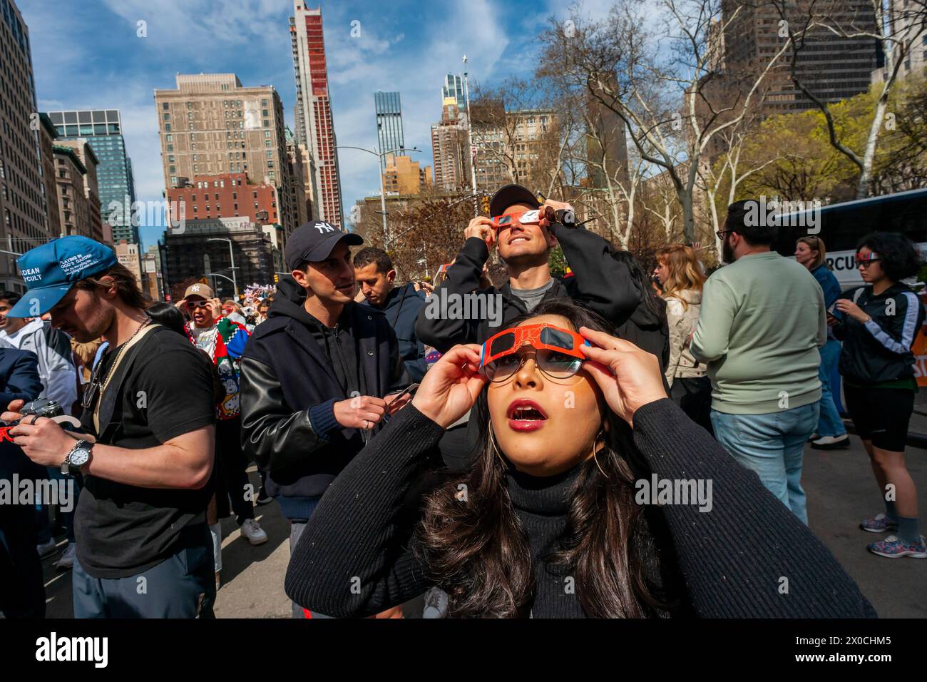 Des centaines de personnes se rassemblent à Flatiron Plaza à New York pour une fête d'observation à regarder, portant leurs lunettes de protection, l'éclipse solaire le lundi 8 avril 2024. New York City n'était pas sur le chemin de la totalité avec la lune couvrant 89% du soleil pendant la fenêtre de 15h15 à 15H30. (© Richard B. Levine) Banque D'Images