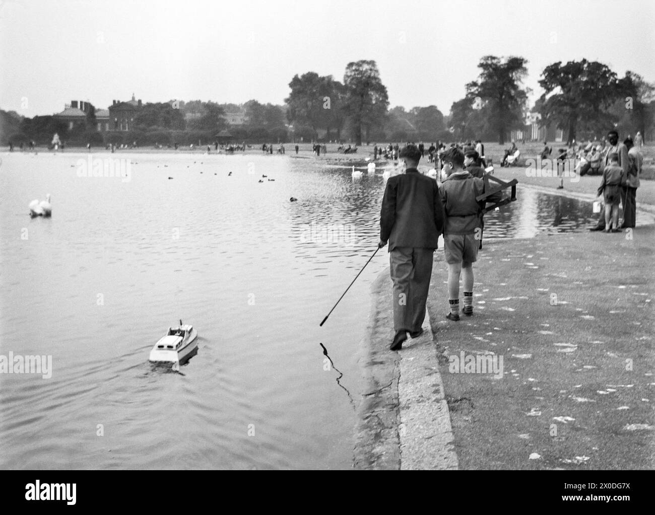 Londres, Angleterre. Garçons avec un bateau modèle sur le Round Pond dans les jardins de Kensington, 1951 Banque D'Images