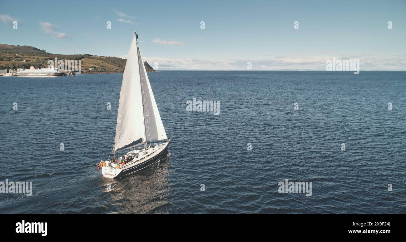 Gros plan lent d'un voilier à l'antenne du golfe océanique. Yacht de course à Sea Bay. Paysage marin majestueux sur un voilier de luxe à Brodick Pier, Arran Island shore, Écosse, Europe. Croisière estivale cinématographique Banque D'Images