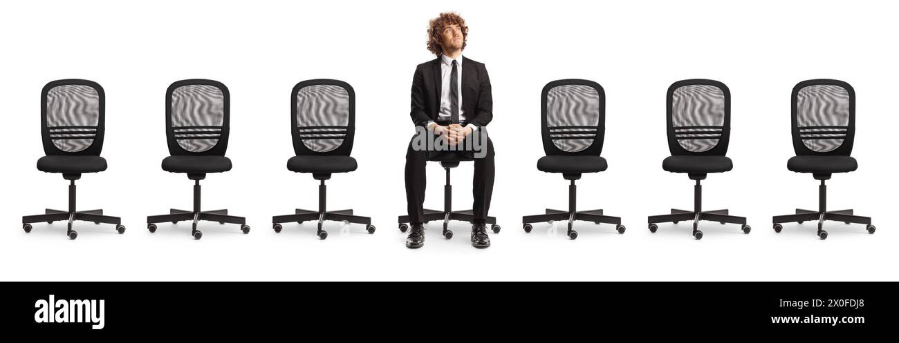 Chaises de bureau vides et un jeune homme professionnel assis au milieu et regardant isolé sur fond blanc Banque D'Images