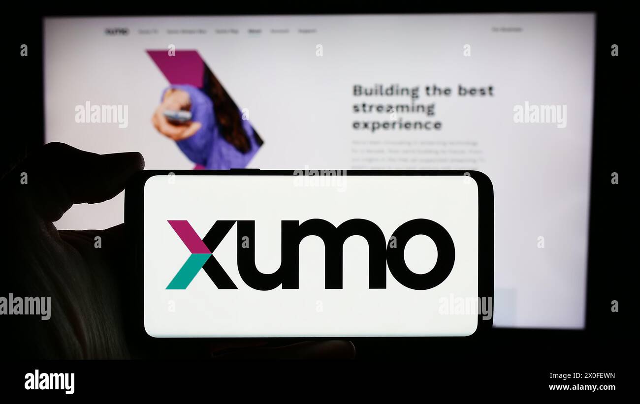Personne tenant le téléphone portable avec le logo de la société américaine de streaming vidéo et de télévision Xumo LLC en face de la page Web. Concentrez-vous sur l'affichage du téléphone. Banque D'Images