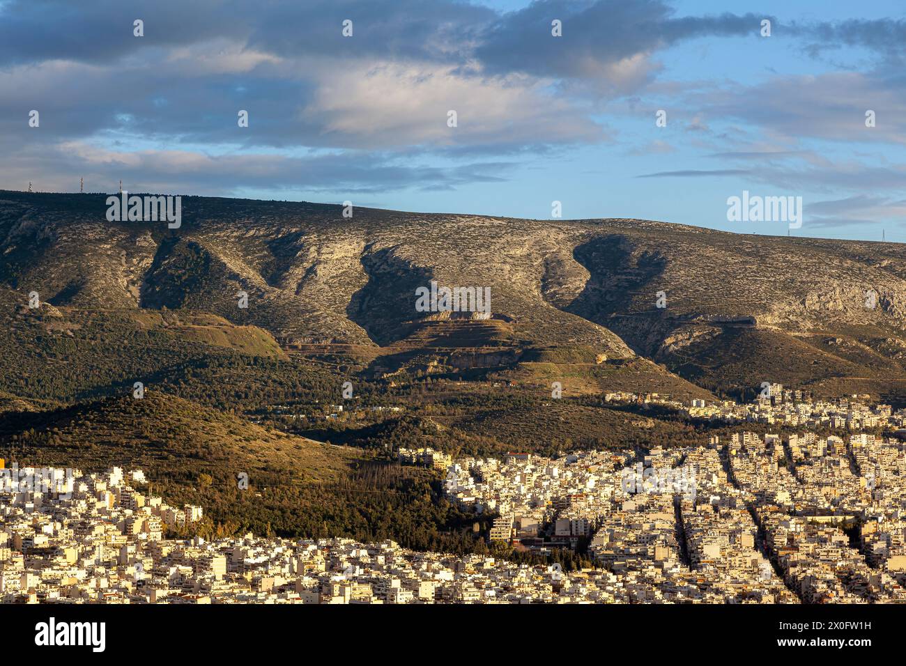 Coucher de soleil majestueux avec de merveilleux nuages sur le mont Hymettus et la ville d'Athènes, Grèce. Il y a plusieurs districts inclus comme Ilioupoli et Kesariani. Banque D'Images