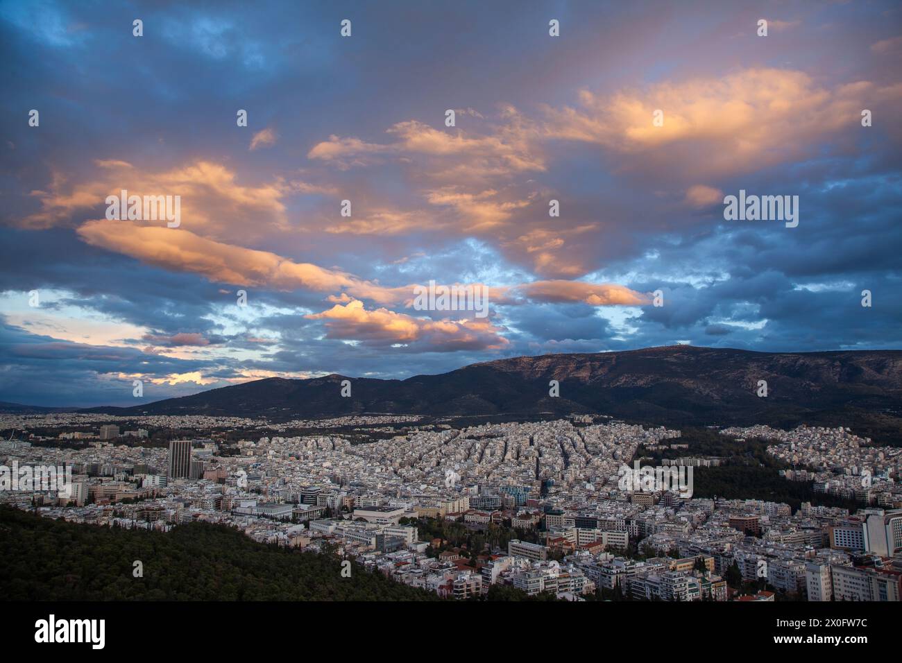 Coucher de soleil majestueux avec de merveilleux nuages sur le mont Hymettus et la ville d'Athènes, Grèce. Il y a plusieurs districts inclus comme Zografou et Papagou. Banque D'Images