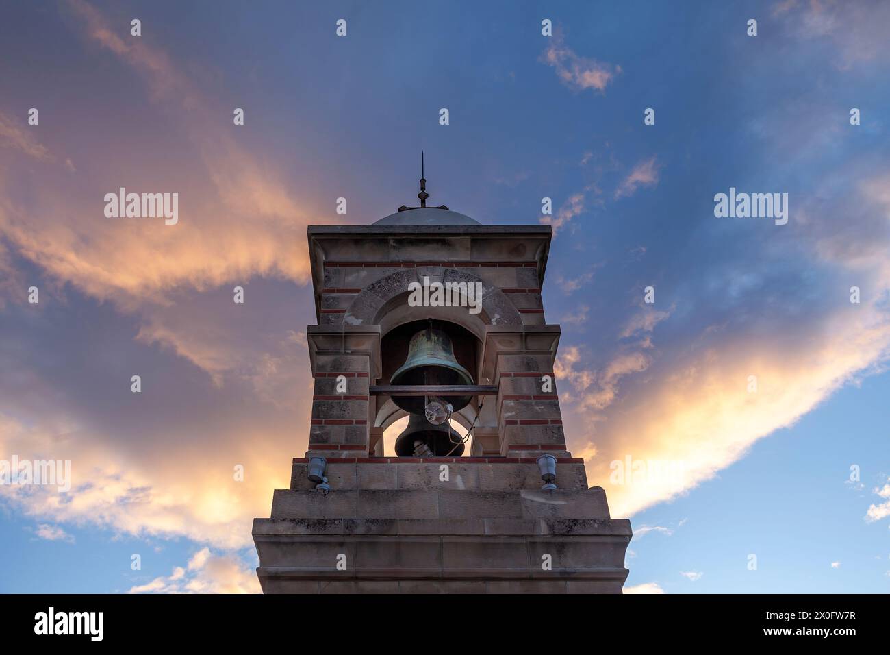 Beffroi en pierre avec cloche en bronze au sommet du mont Lycabette, Athènes, lors d'un coucher de soleil glorieux avec des nuages colorés. Banque D'Images