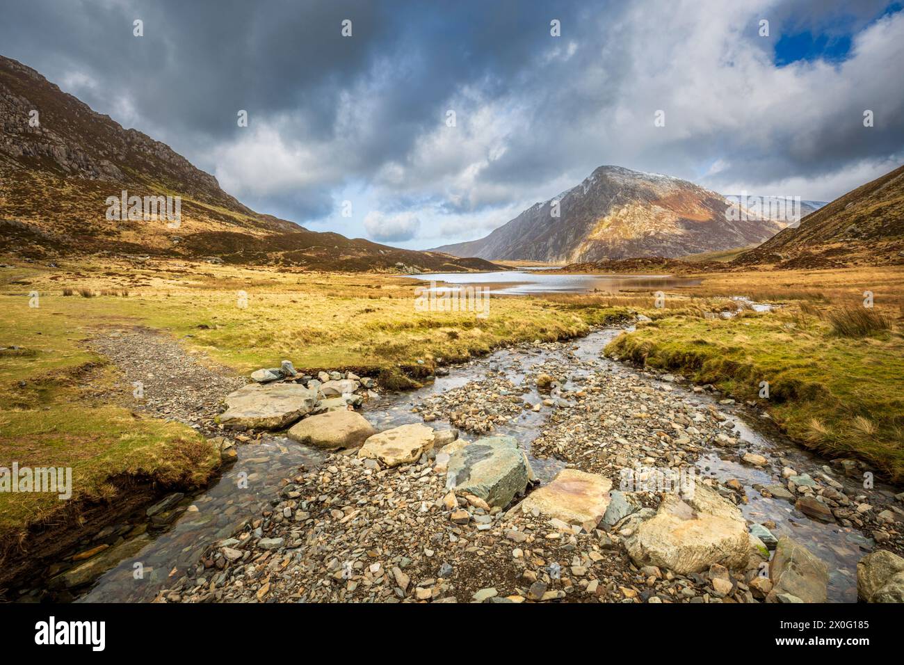 Tremplin à travers un ruisseau de montagne menant à Llyn Idwal dans la réserve naturelle de Cwm Idwal avec la montagne Pen yr Ole Wen en arrière-plan, Snowdonia, Banque D'Images