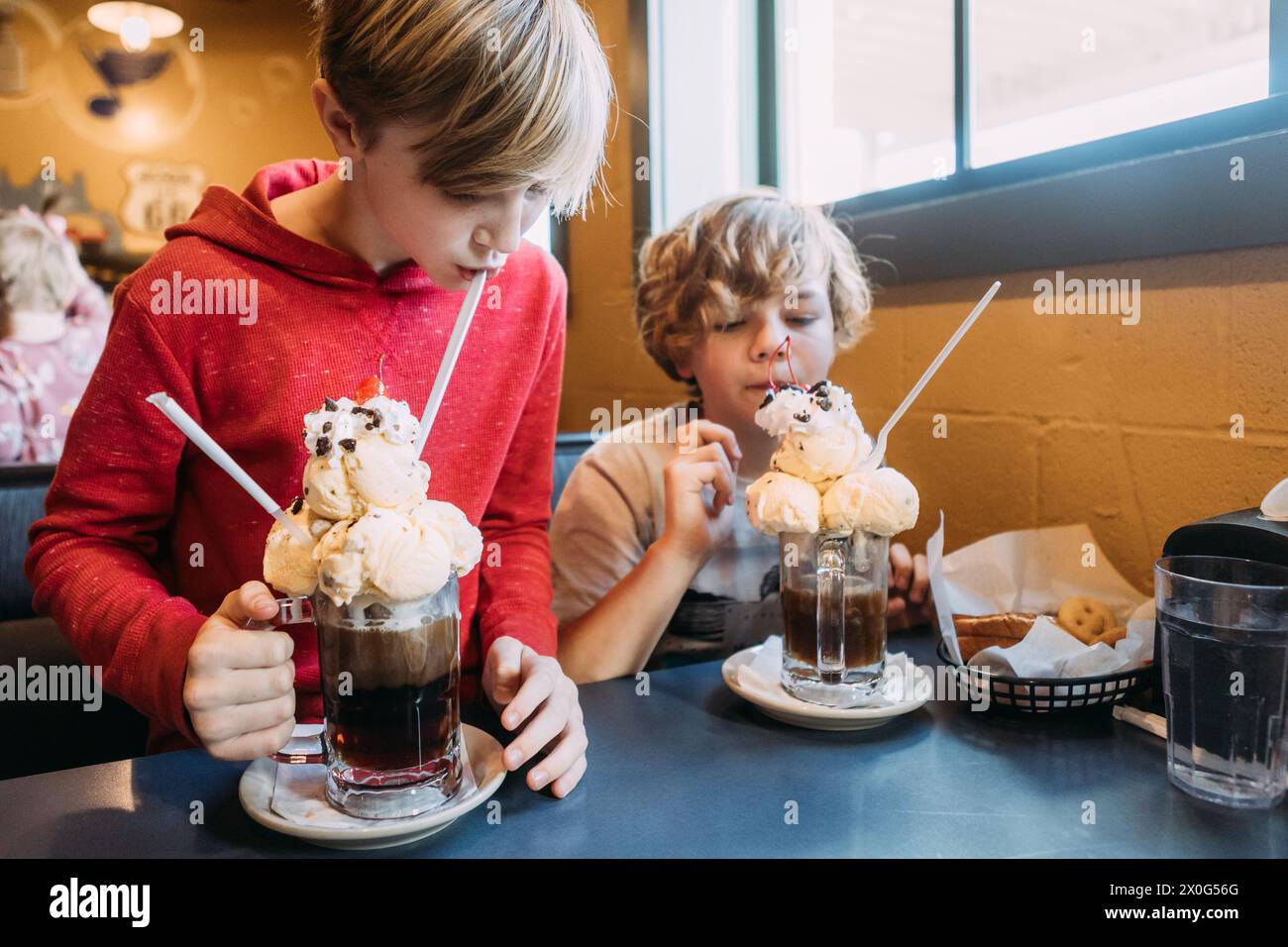 Les enfants buvant des chars de rootbeer amusants avec de la crème glacée au restaurant Banque D'Images
