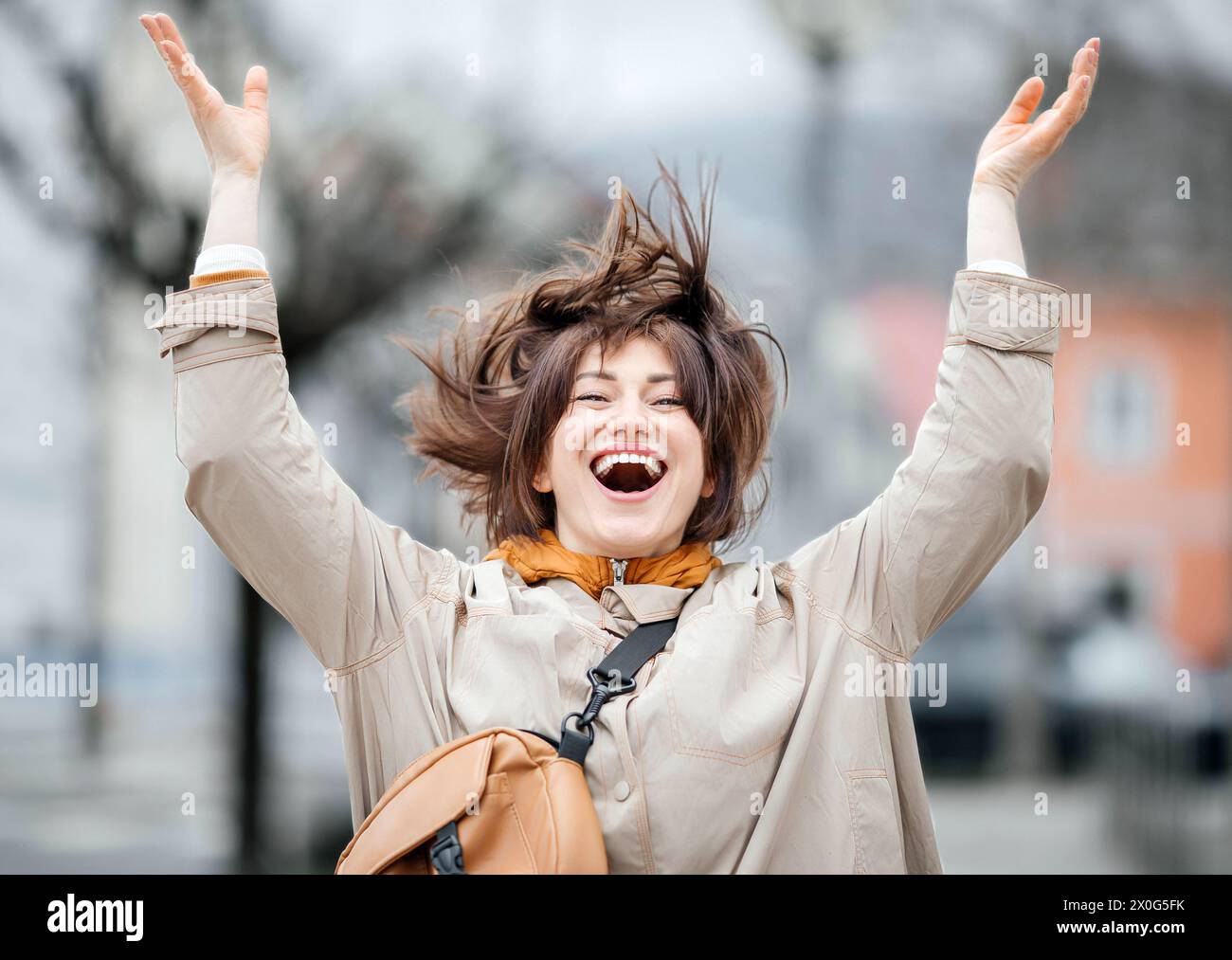 Extatique jeune femme célébrant avec les bras levés dans la ville Banque D'Images