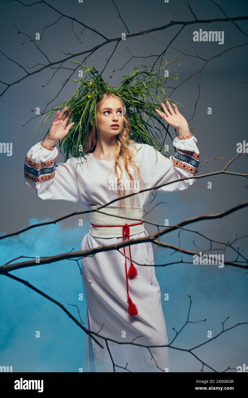 Une jeune mavka dans une robe blanche orne sa tête d'une couronne de feuilles dans un cadre de studio inspiré de la fée et de la fantaisie. Banque D'Images