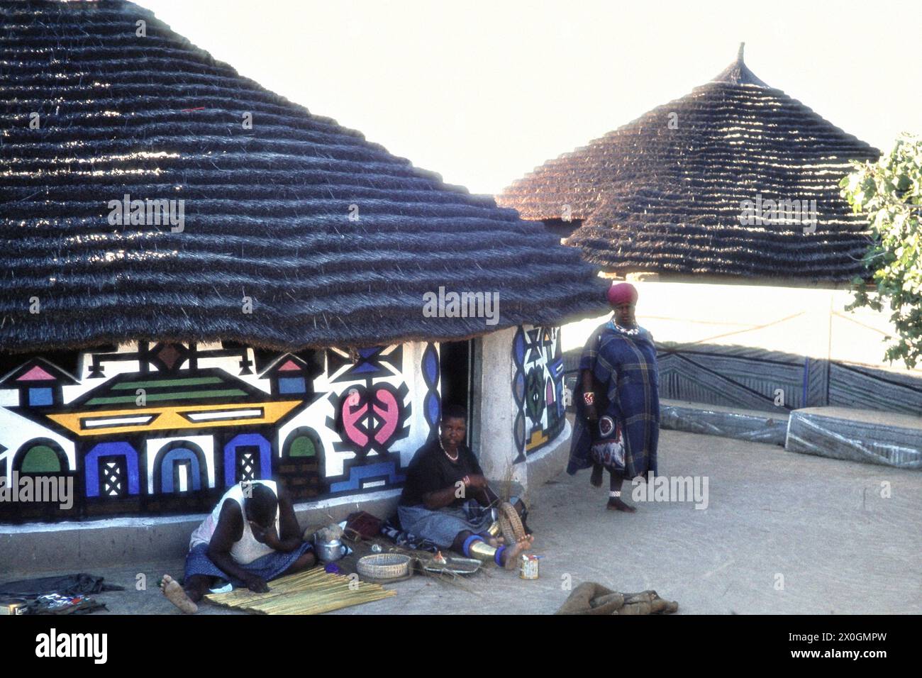 Les femmes qui travaillent devant une cabane peinte dans un village de Ndebele. [traduction automatique] Banque D'Images