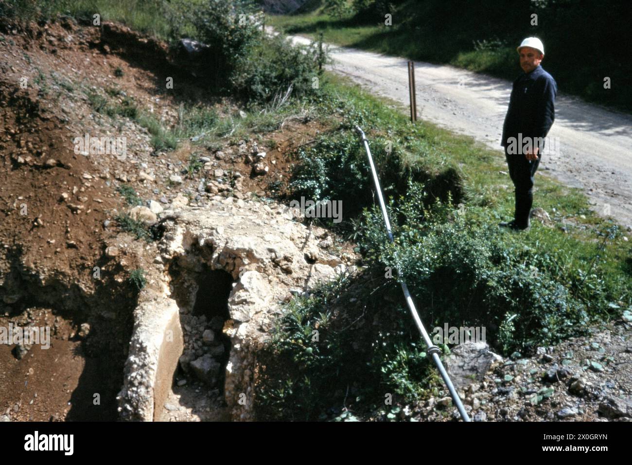 Un ouvrier de la construction se tient devant le virage dans les restes d'un tuyau d'eau romain dans l'Eifel près de Sötenich. [traduction automatique] Banque D'Images