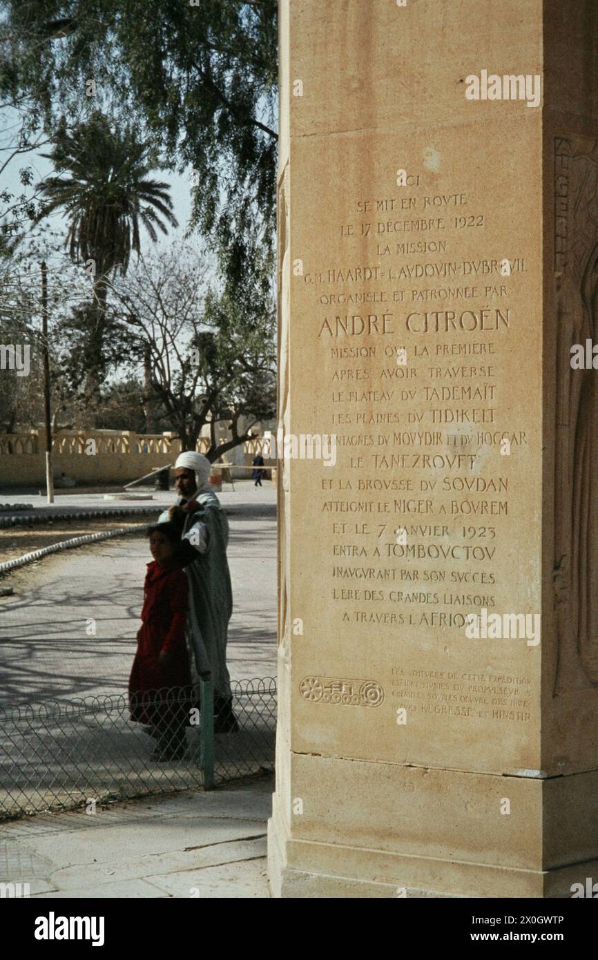 Père et fille en vêtements traditionnels en face d'une colonne de Touggourt, qui rappelle le Sahara expédition d'André Citroën. Banque D'Images