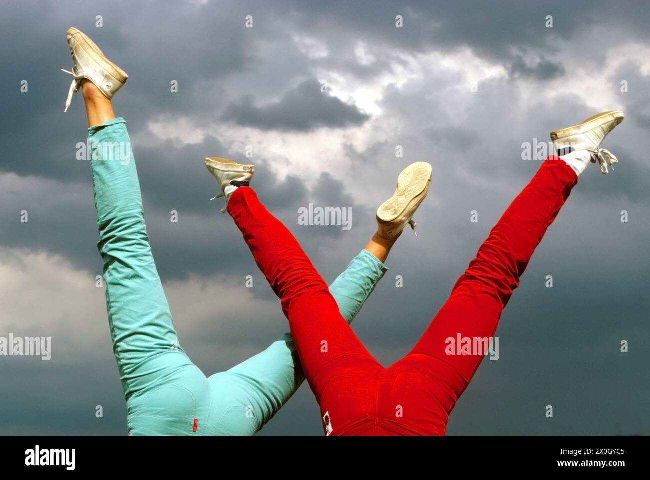 Deux jeunes femmes étirent leurs jambes dans l'air pour la joie et la soif de vie. [traduction automatique] Banque D'Images