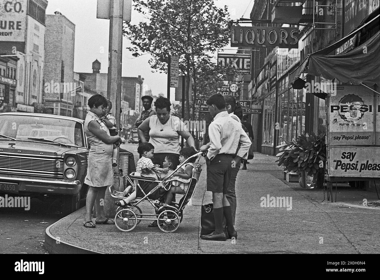 Une famille avec trois enfants dans une poussette à un coin de rue à New York district Harlem. Banque D'Images