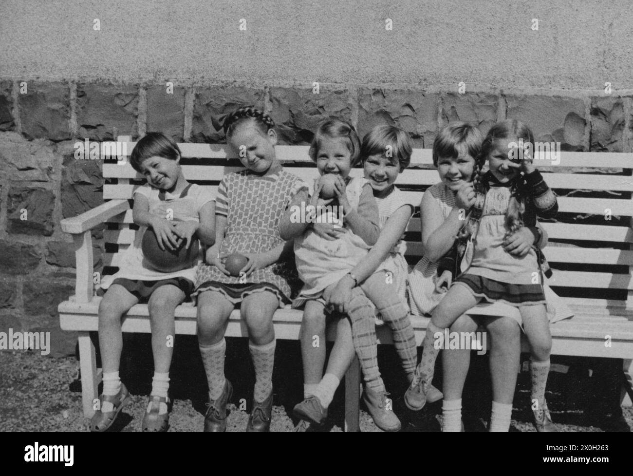 Enfants heureux avec des balles assis sur un banc dans le Sauerland (photo non datée). Banque D'Images