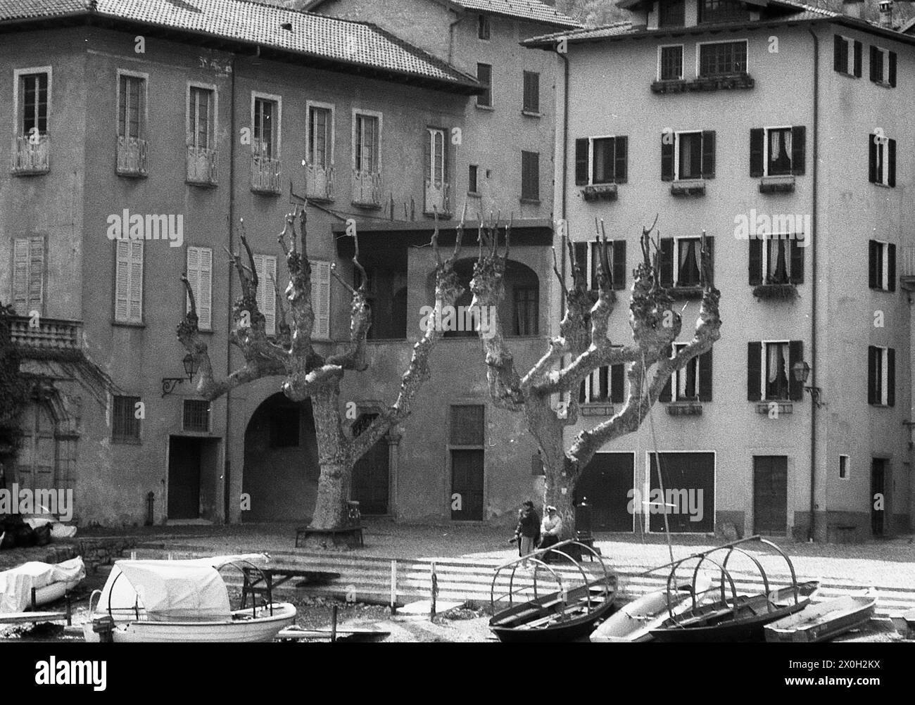 Hommes et bateaux dans une petite ville portuaire sur le lac de Côme en Italie. Banque D'Images