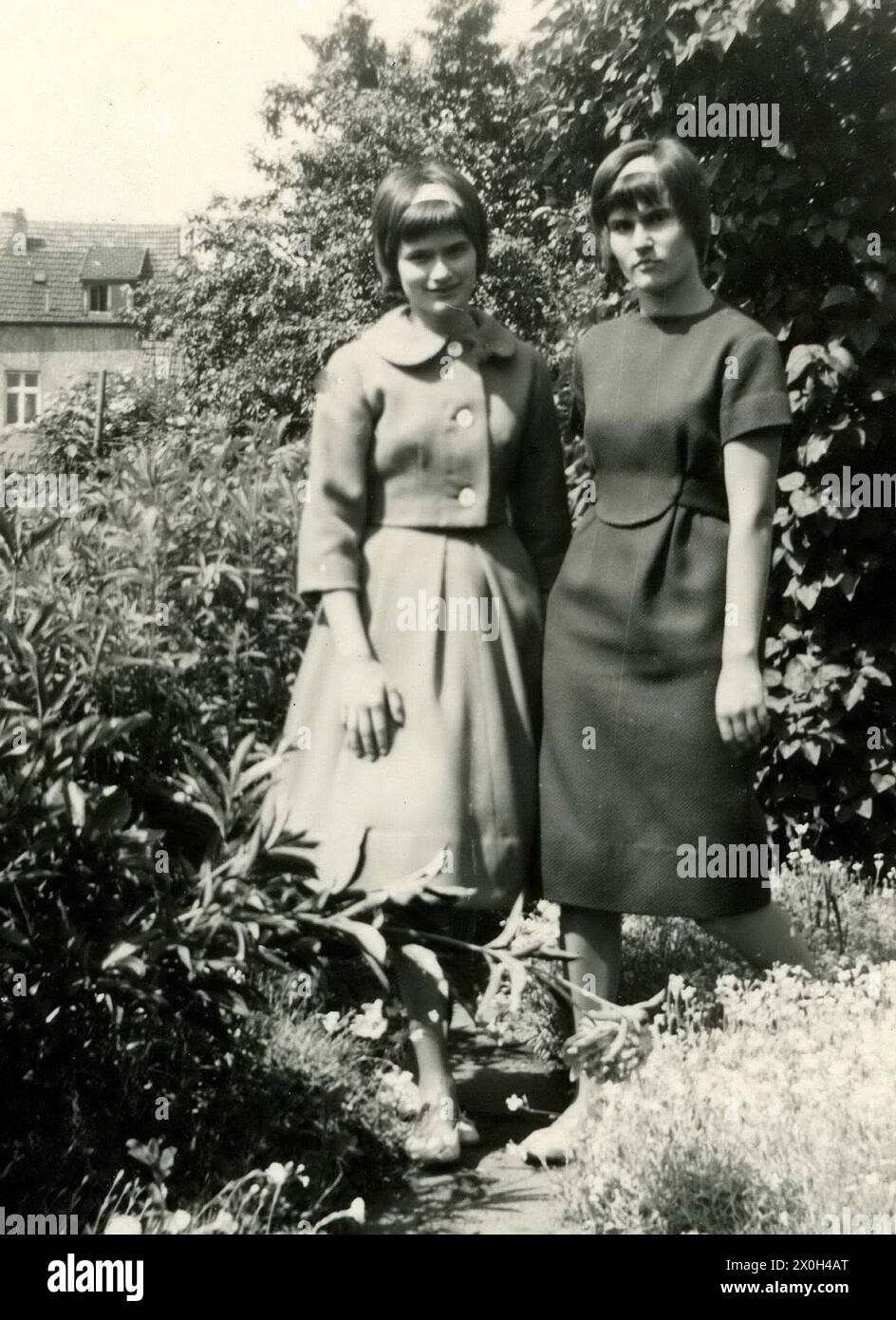 Deux sœurs sont debout dans le jardin de leurs parents posant pour une photo. La fille à droite porte une nouvelle robe que sa mère cousue pour son diplôme. [traduction automatique] Banque D'Images