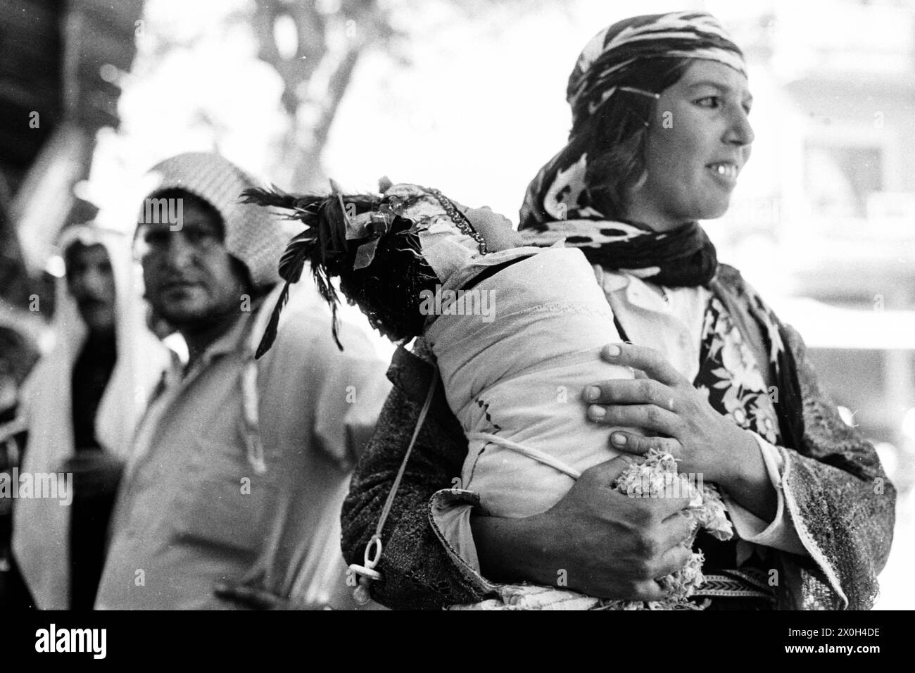 Une mère porte son bébé traditionnellement emmailloté. [traduction automatique] Banque D'Images