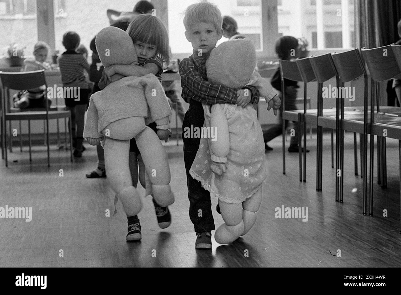 Un garçon et une fille tiennent fermement leurs poupées grandeur nature dans leurs bras [traduction automatique] Banque D'Images