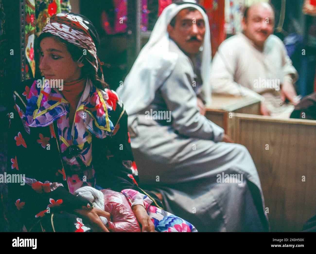 Une jeune fille vêtue d'un costume bédouin est regardée par deux hommes. [traduction automatique] Banque D'Images