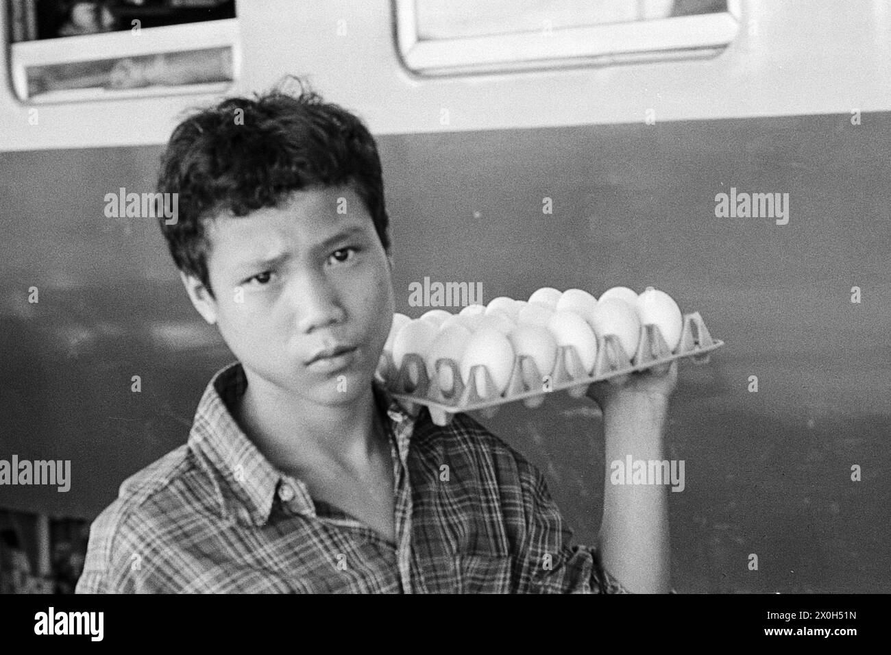 À la gare de Surat Thani en Thaïlande : un colporteur tente de vendre ses œufs durs. [traduction automatique] Banque D'Images