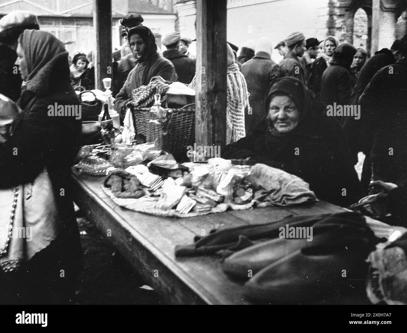 Une vieille femme offre ses biens dans un étal couvert du marché. Autour d'elle se trouvent d'autres vendeurs et visiteurs du marché. La photo a été prise par un membre du Radfahrgrenadierregiment 2 / Radfahrsicherungsregiment 2, sur le front est. [traduction automatique] Banque D'Images