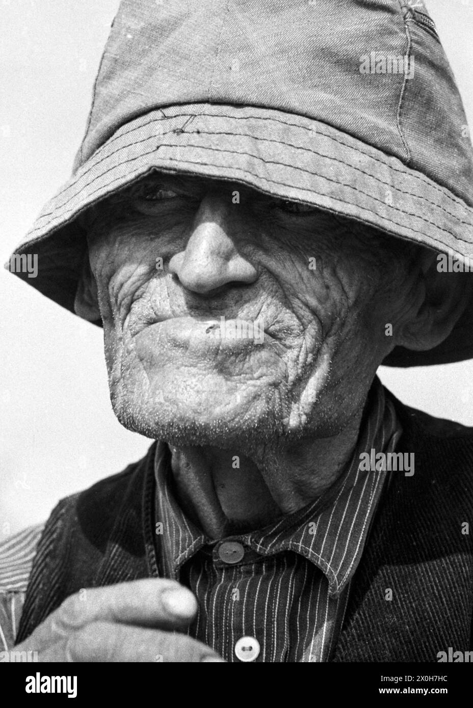 Un vieil homme en Espagne a tiré son chapeau bas sur son visage pour se protéger du soleil. Une mouche est assise sur sa lèvre inférieure. [traduction automatique] Banque D'Images