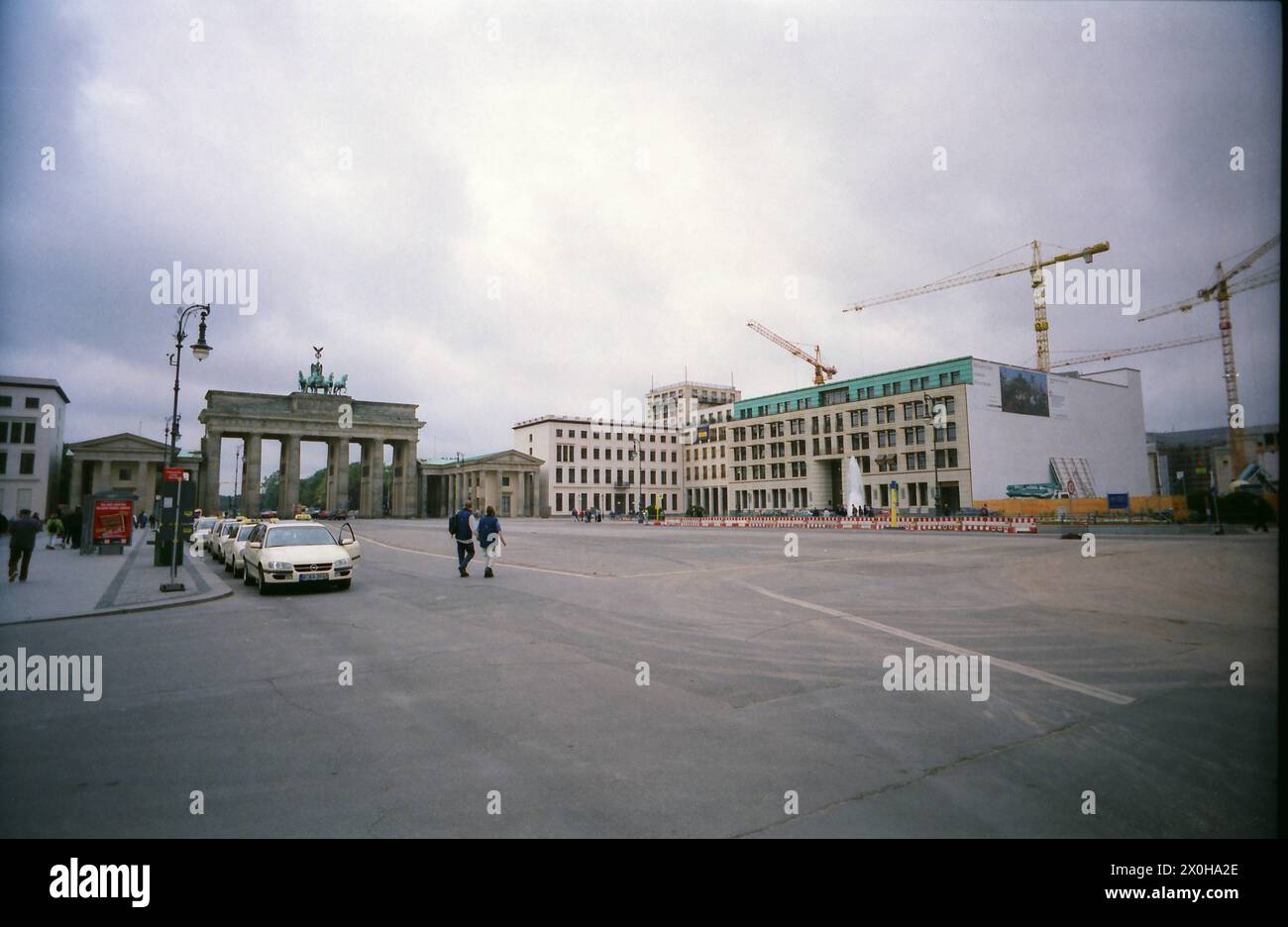La porte de Brandebourg sur Pariser Platz. Quelques grues se trouvent sur les chantiers autour de la porte de Brandebourg. Les taxis attendent au bord de la route. [traduction automatique] Banque D'Images