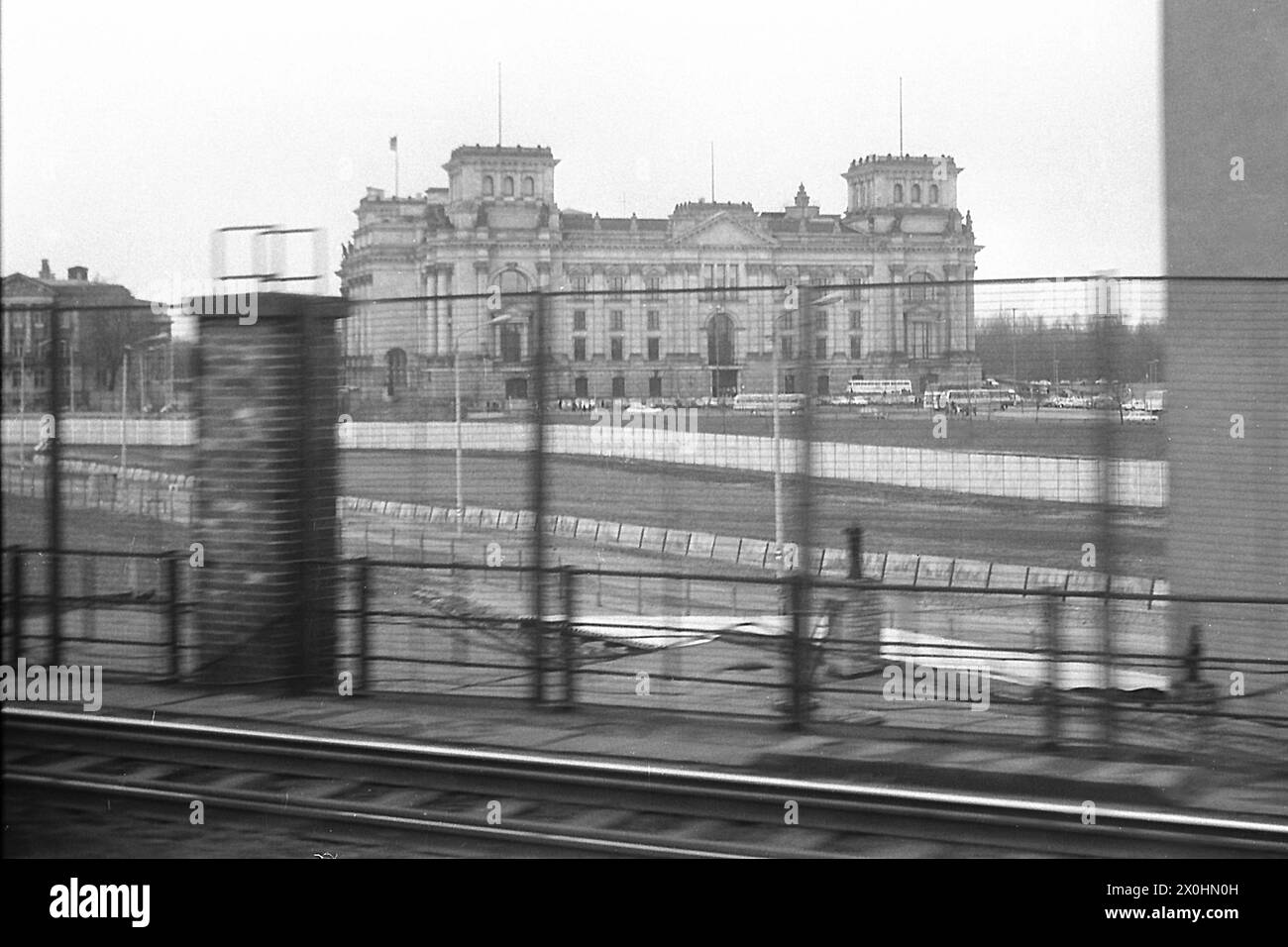 Ceci est une photo de l'histoire contemporaine. Le S-Bahn et le train longue distance circulaient entre les gares Friedrichstrasse et Lehrter Bahnhof, à la frontière entre l'est et l'Ouest. Vous pouvez voir les fortifications frontalières du côté est avec des clôtures le long des voies et des murs jusqu'au mur final sur la rive nord de la Spree. Berlin-Ouest a seulement commencé sur la rive sud de la Spree, à peine visible ici et qui était le défait des réfugiés qui croyaient que la frontière était au milieu de la rivière. Derrière lui, le Reichstag est resté sans nouveau dôme pendant de nombreuses années. [automatisé Banque D'Images