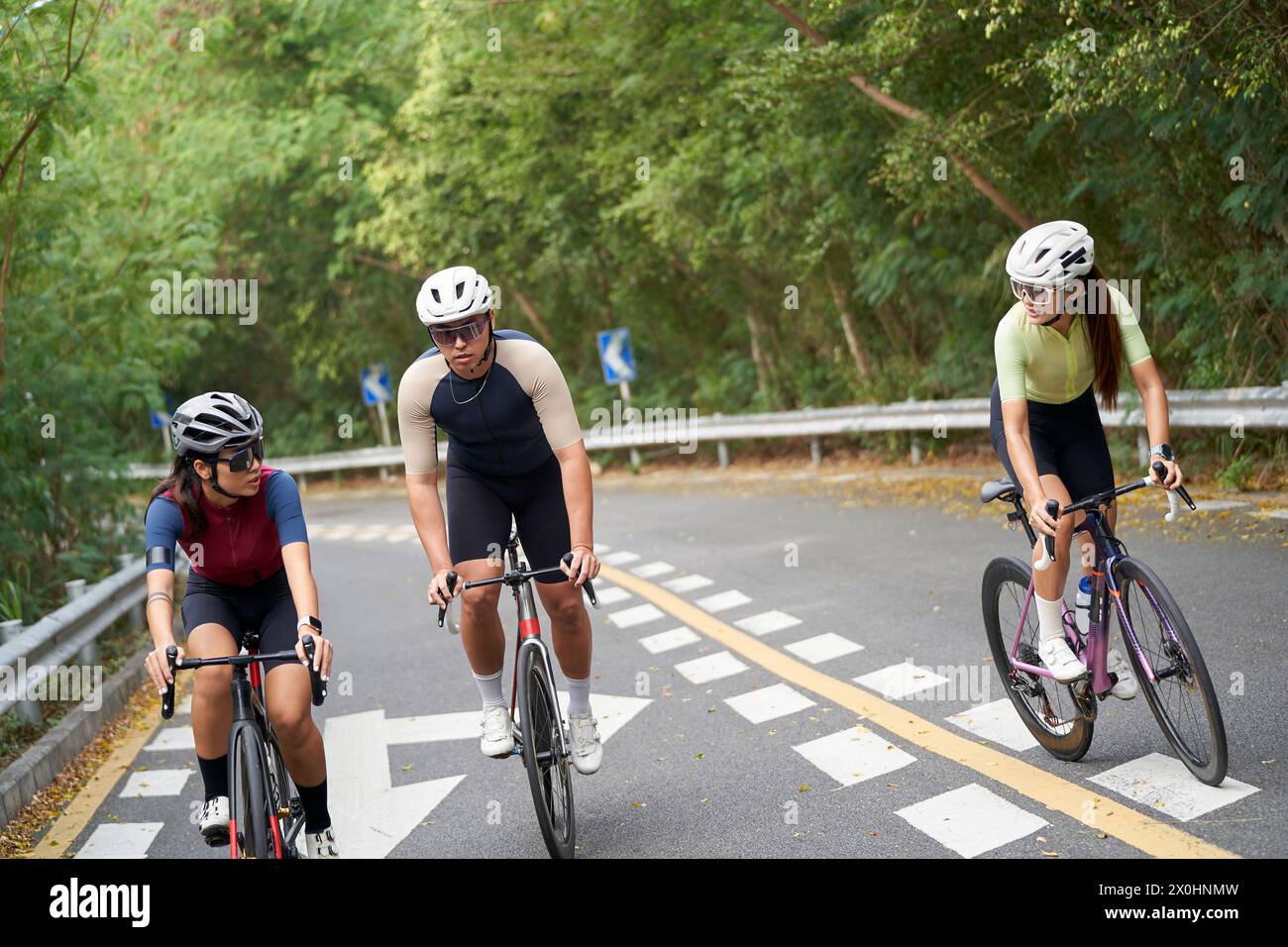 trois jeunes cyclistes asiatiques faisant du vélo à l'extérieur sur la route rurale Banque D'Images