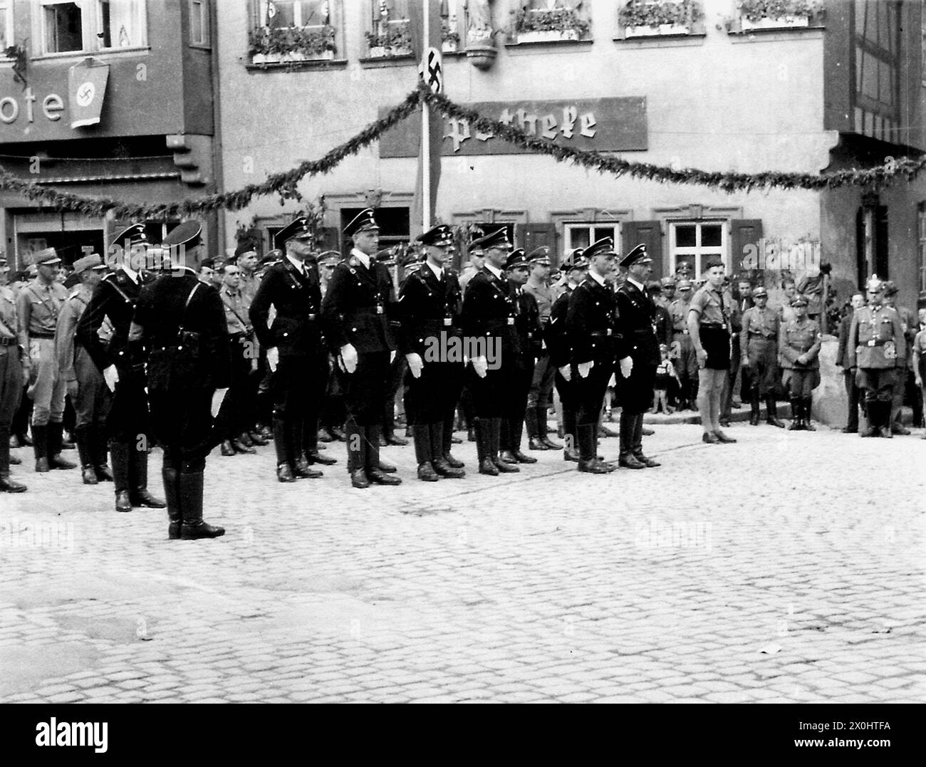Une formation du Schutzstalockel (SS) avec sa et des troupes de travail en arrière-plan et une jeunesse Hitler à côté de lui dans la procession pour la fête du travail devant la mairie d'Ochsenfurt. [traduction automatique] Banque D'Images