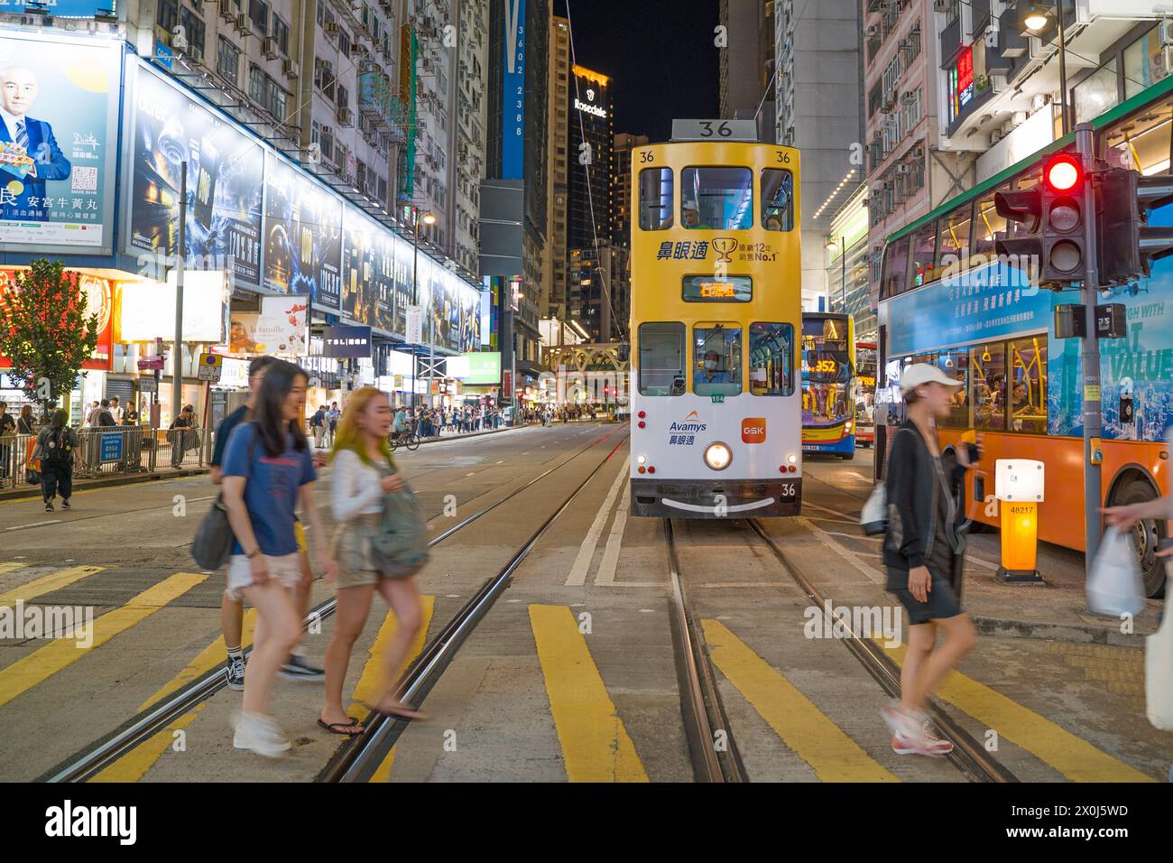 Causeway Bay la nuit avec un tramway jaune dans la route et les gens qui traversent le passage. Hong Kong - 28 août 2023 Banque D'Images