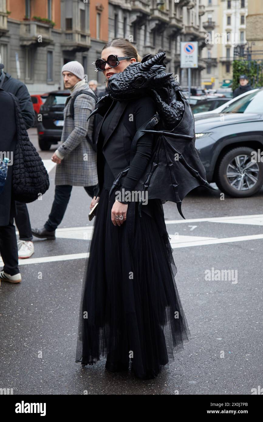 MILAN, ITALIE - 23 FÉVRIER 2024 : femme avec veste noire et jupe en mousseline de soie avec sac à dos dragon Before Philosophy par Lorenzo Serafini défilé, Banque D'Images