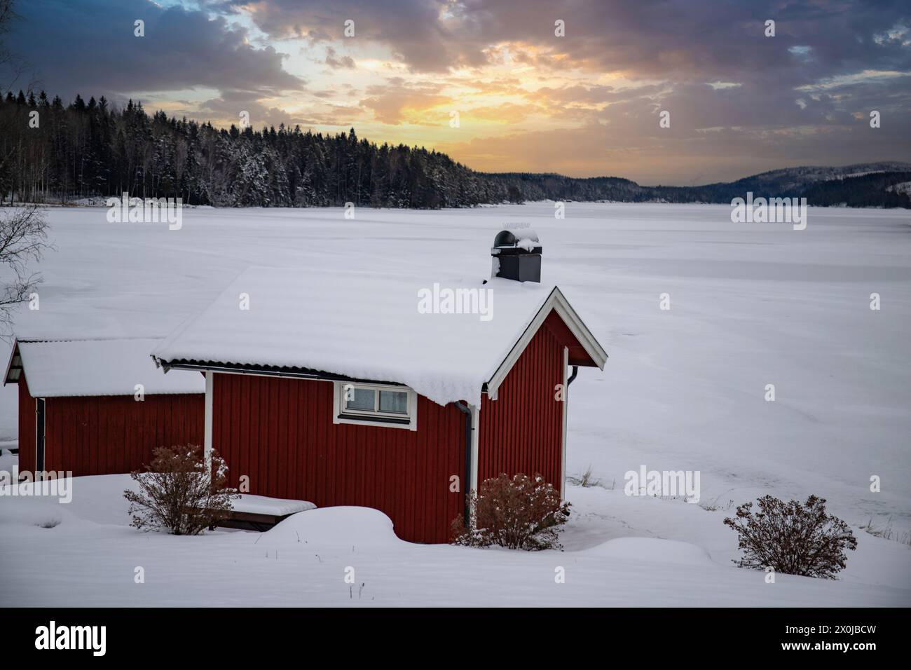 Maison suédoise rouge typique. Maison en bois dans un paysage d'hiver avec de la glace et de la neige. Petite colonie au milieu d'une forêt enneigée. Paysage photographié en Suède Banque D'Images