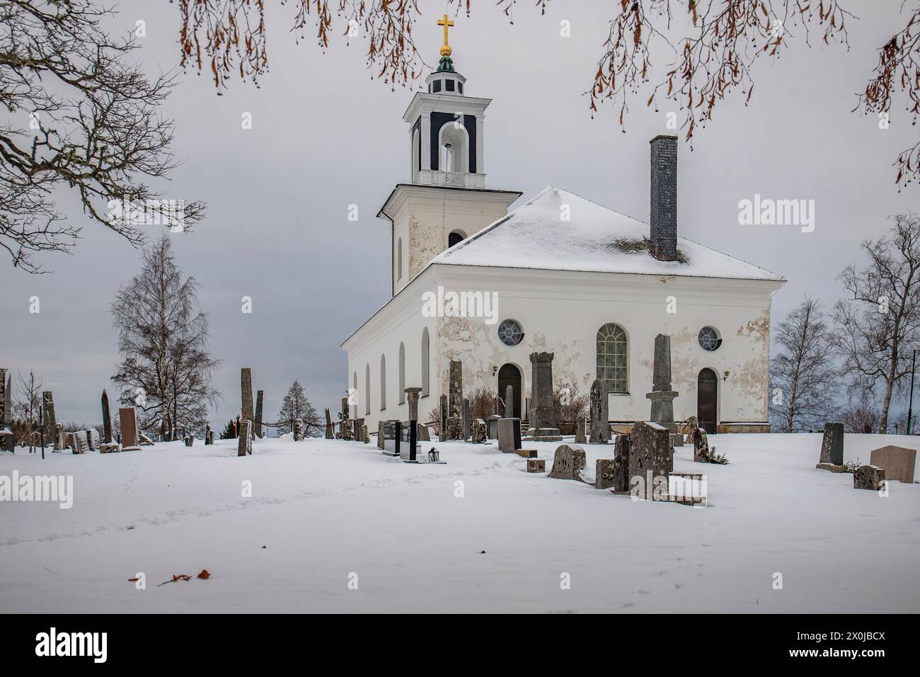 Petite église blanche sur un lac gelé dans un paysage hivernal froid avec de la neige et de la glace. Varviks kyrka, Suède Banque D'Images