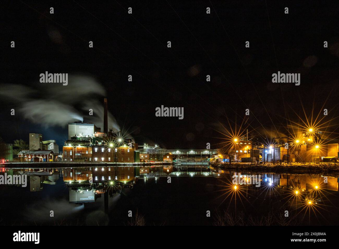 Usine de papier la nuit. Photo d'hiver d'une petite usine avec reflet dans un lac. Scène nocturne à Bengtsfors, Suède Banque D'Images