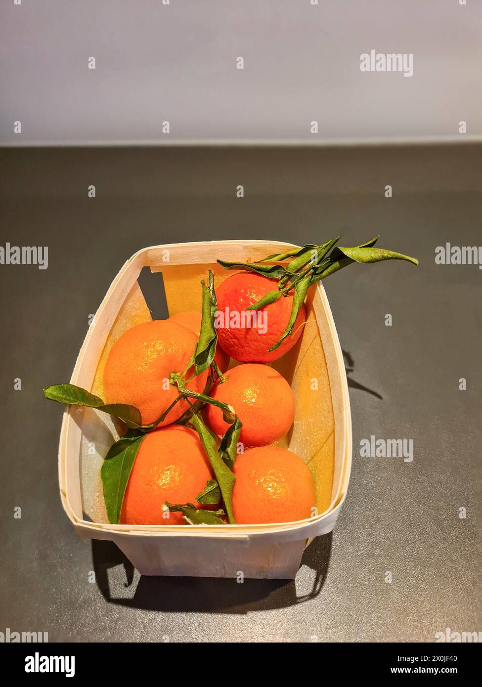 Les fruits oranges de la clémentine ou des mandarines emballés dans une boîte avec des feuilles pour la consommation Banque D'Images