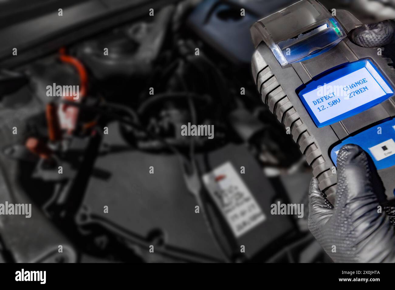 Explorez les diagnostics automobiles pendant qu'un mécanicien tient un testeur de batterie sous le capot, affichant les défauts et les changements sur l'écran au-dessus de la batterie de la voiture, Banque D'Images