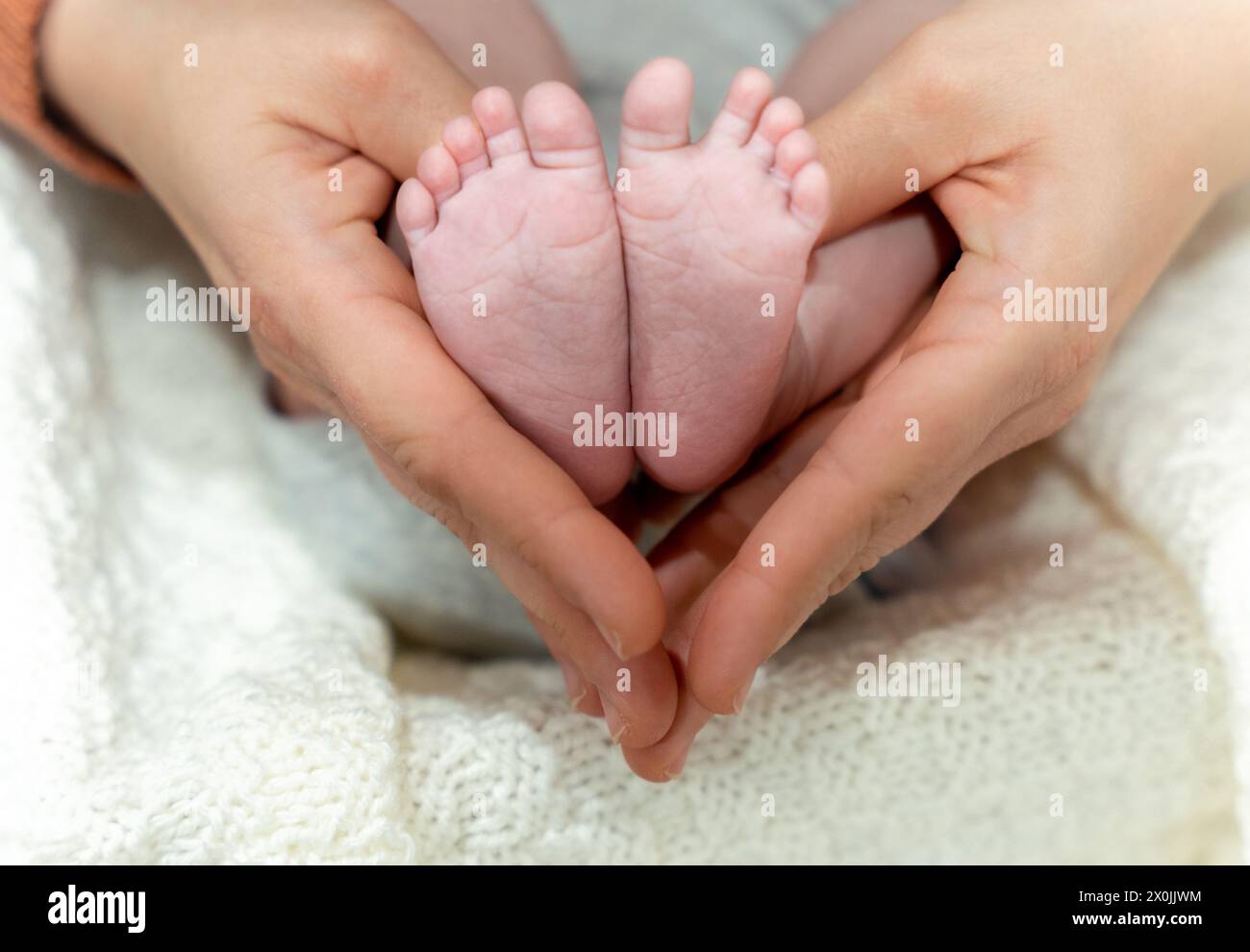 Mains de mère tenant les pieds du nouveau-né en forme de coeur Banque D'Images