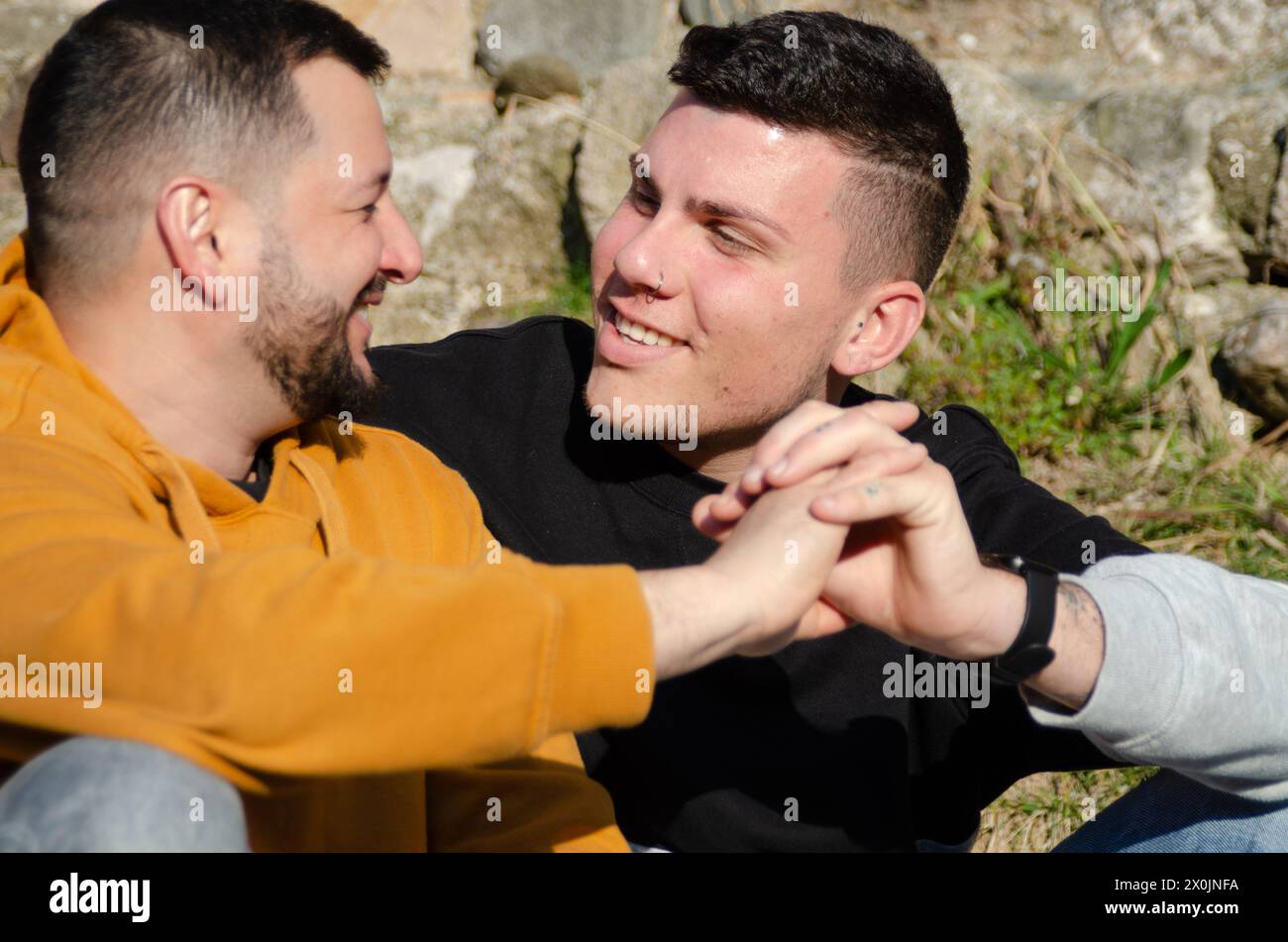 Les hommes gays couples amoureux se regardent les yeux les uns les autres et joignent la main. Homosexualité et concept LGBTQ+. Banque D'Images