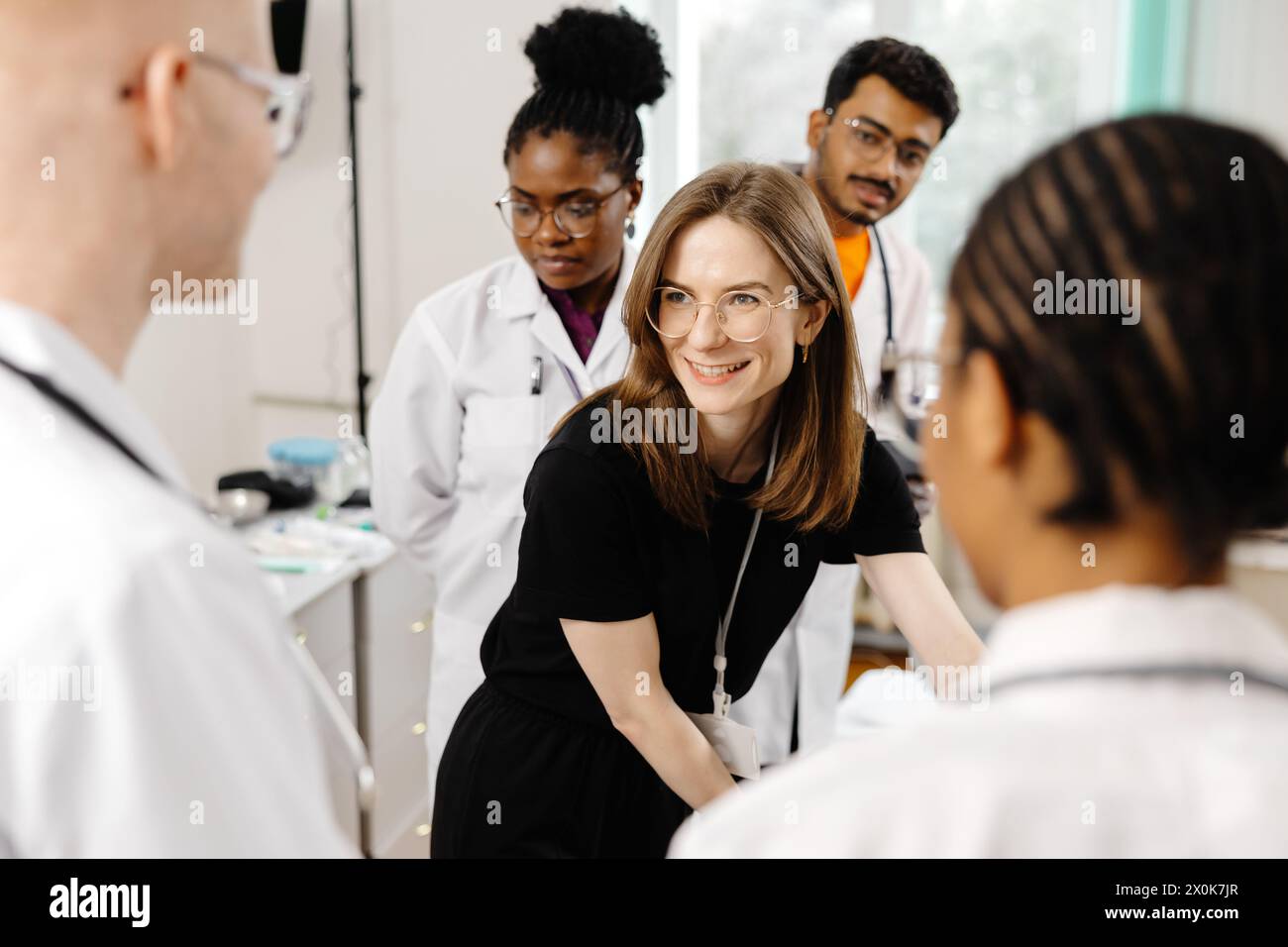 Une femme vêtue d'une robe noire est soignée par un groupe de médecins, qui se tiennent autour d'elle de manière sérieuse, discutant peut-être de son état médical Banque D'Images
