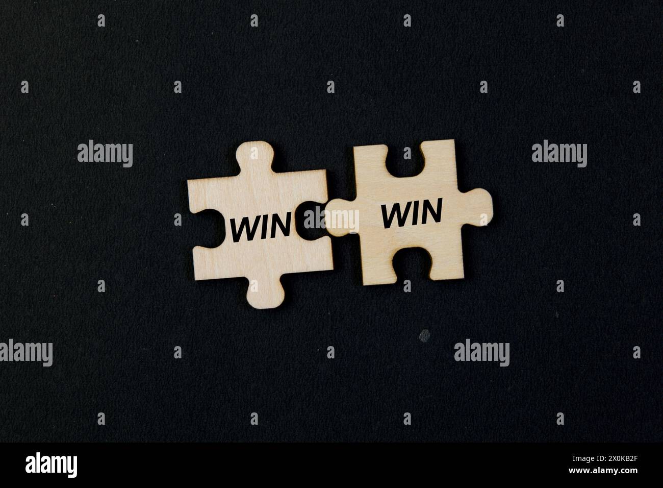 Gros plan de deux pièces de puzzle s'assemblant pour créer le texte « Win Win » sur fond noir Banque D'Images