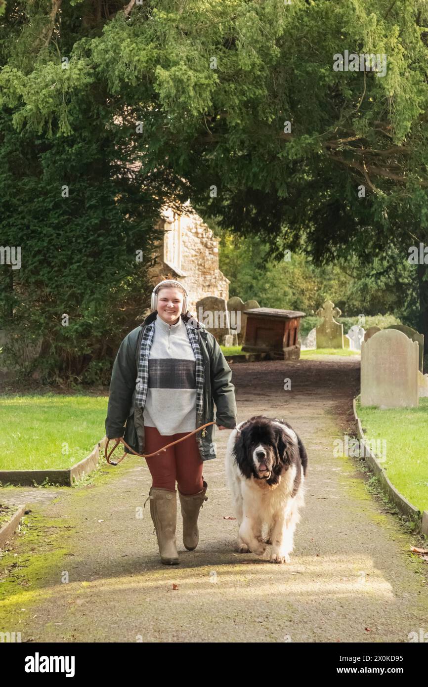 Angleterre, Kent, Edenbridge, Hever, Église Saint-Pierre, femme marchant chien dans Church Yard Banque D'Images
