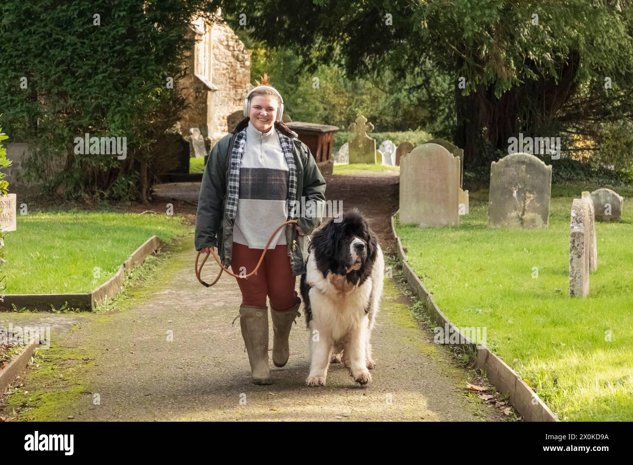 Angleterre, Kent, Edenbridge, Hever, Église Saint-Pierre, femme marchant chien dans Church Yard Banque D'Images