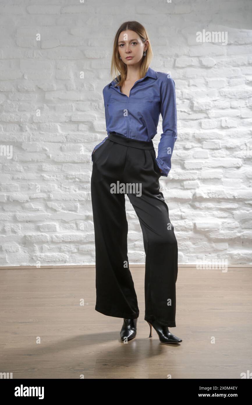 Photo de studio d'une femme portant une chemise en Jean de coton et un pantalon noir large. Banque D'Images