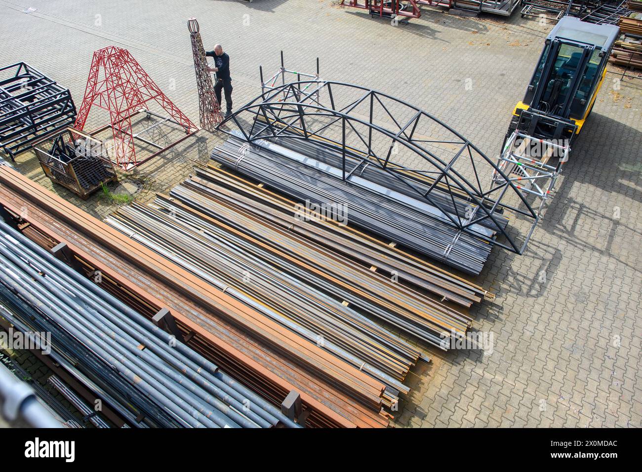 PRODUCTION - 12 avril 2024, Saxe-Anhalt, Magdebourg : Andreas Lück, serrurier du Théâtre de Magdebourg, place le sommet de la Tour Eiffel dans la cour des ateliers du théâtre comme fondation pour la construction. À côté, on peut voir des pièces en acier et une arche pour la construction en acier de la scène Domplatz Open-Air. La Domplatz Open-Air célèbre sa première le 14 juin 2024 avec la comédie musicale « Love Never Dies ». C'est la suite de la comédie musicale « fantôme de l'Opéra ». Théâtre Magdeburg est le premier théâtre municipal à recevoir les droits de représentation pour le succès international Banque D'Images