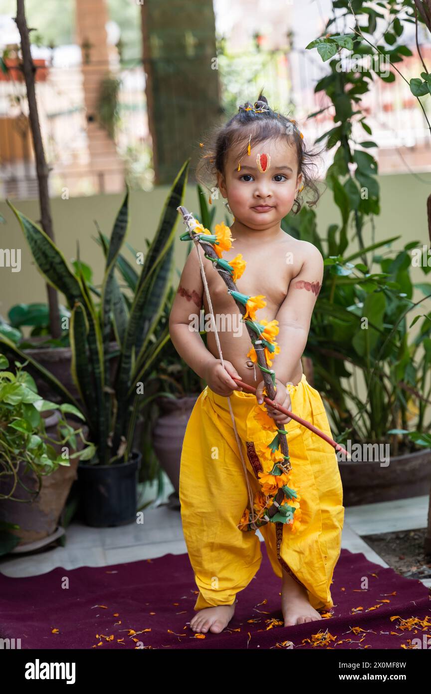 Portrait de mignon garçon indien robes comme seigneur rama avec arc à l'extérieur avec fond flou le jour Banque D'Images