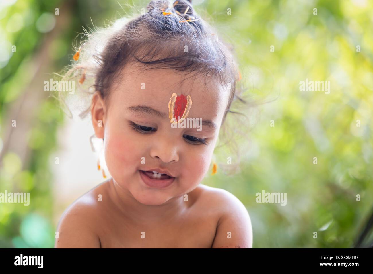 Garçon indien mignon avec symbole religieux sacré sur la tête à l'extérieur avec fond flou Banque D'Images